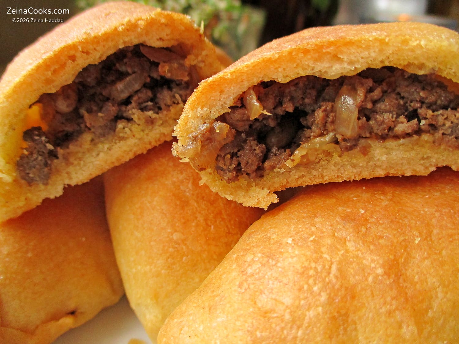 A close-up showing the meat, onion, and pine nut filling of the Lebanese meat pies Fatayer bi Lahmeh, and the airy light crumb of the baked dough by ZeinaCooks.com.