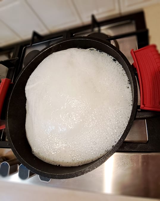 milk foaming up in a pot on the heat for pastry cream