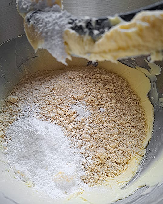 adding almond flour and powdered sugar to butter in a stand mixer for almond cream