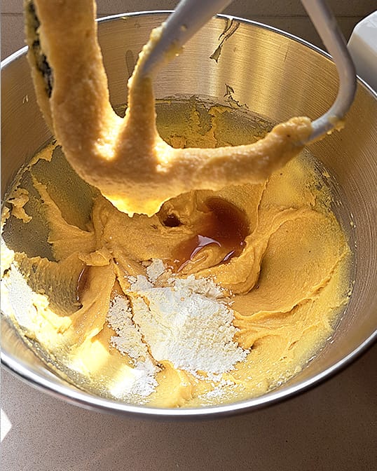 adding cornstarch, rum, and almond extract to almond flour, powdered sugar, butter and eggs in a stand mixer for almond cream