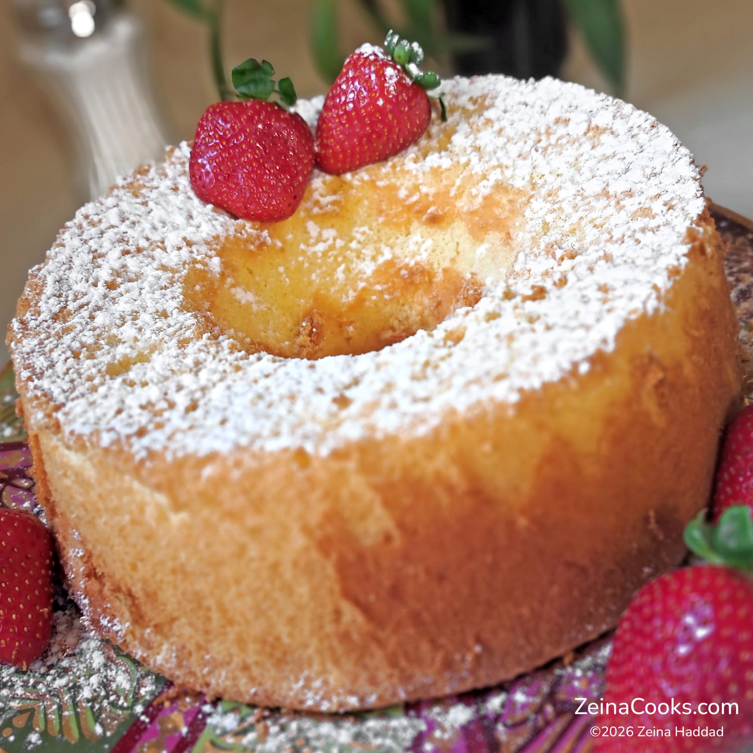 The finished American Sponge Cake, dusted with powdered sugar and decorated with fresh strawberries.