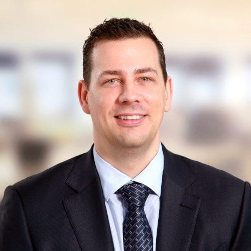 Portrait of a man in a suit with a blurred office background.