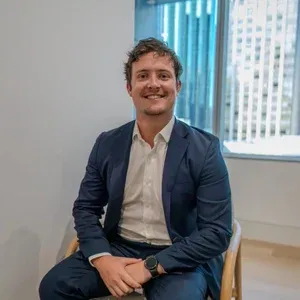 Man with blue suit and white shirt sitting and smiling toward camera