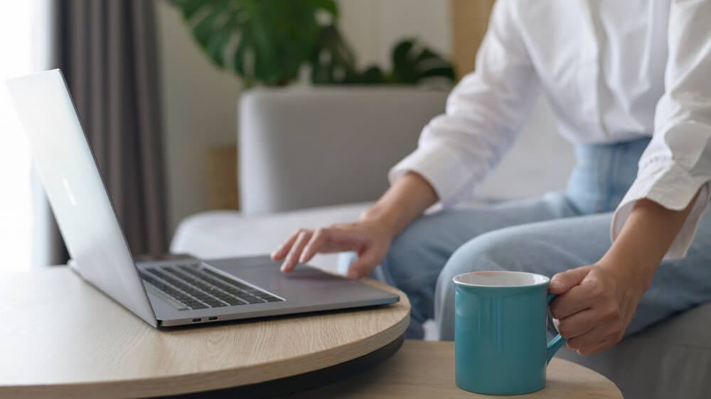 Woman working from home with laptop and coffee