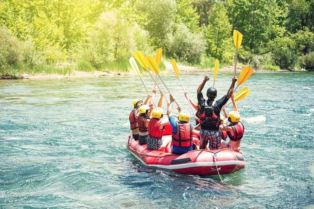 A rafting group raising their paddles in celebration on the river, symbolizing breakthrough, hope, and feeling back in the flow of life again.