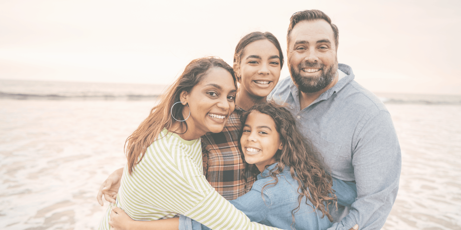 Smiling family hugging on a beach