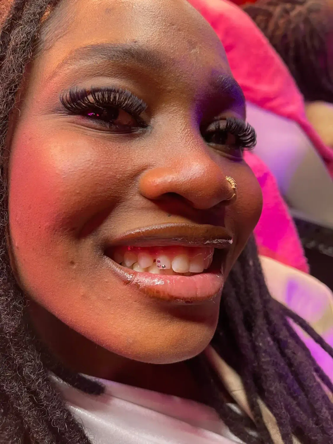 Photo d'une cliente en train de sourire après qu'elle ai reçu une prestation de strass dentaire