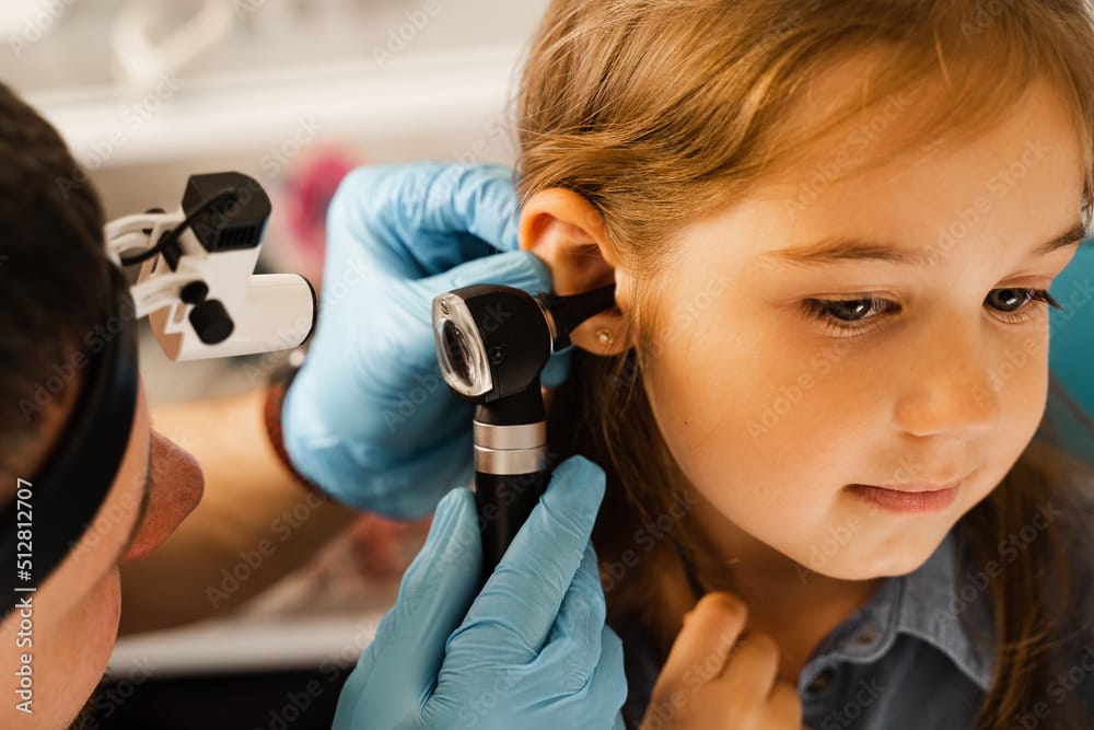 Pediatric ear pain assessment of a child in Kids Health Journey Clinic with doctor face not visible.