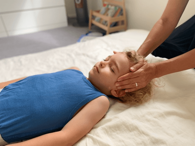 Man giving Reiki to a pregnant woman who is lying on a massage table