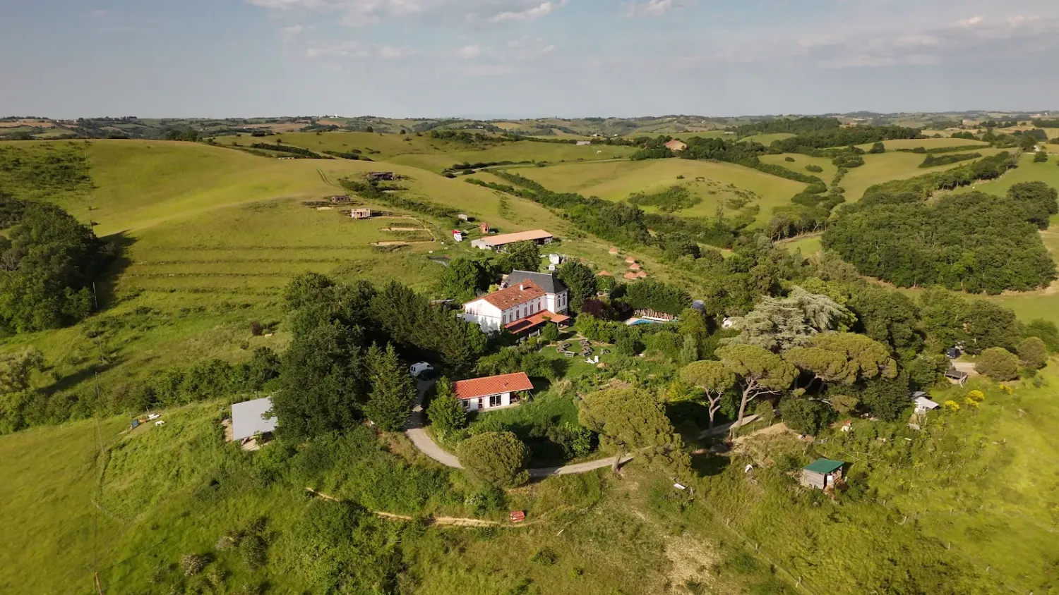 Vue aérienne de l'écovillage de Pourgues, ses maisons et ses collines, en Ariège