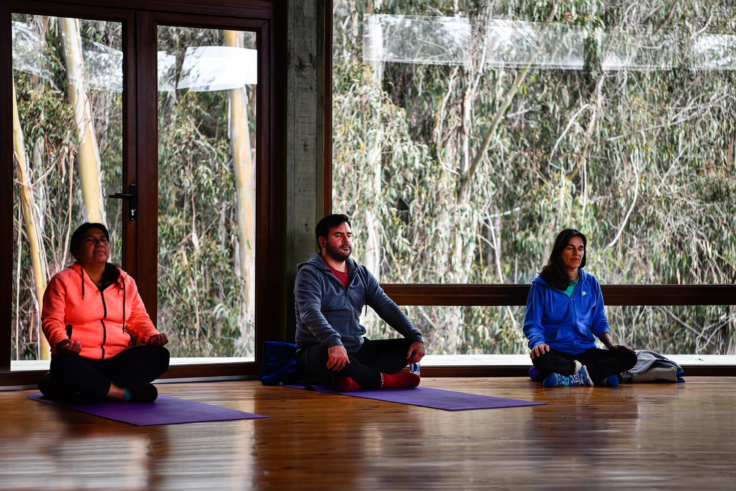 Tres participantes meditando junto a los ventanales durante el taller