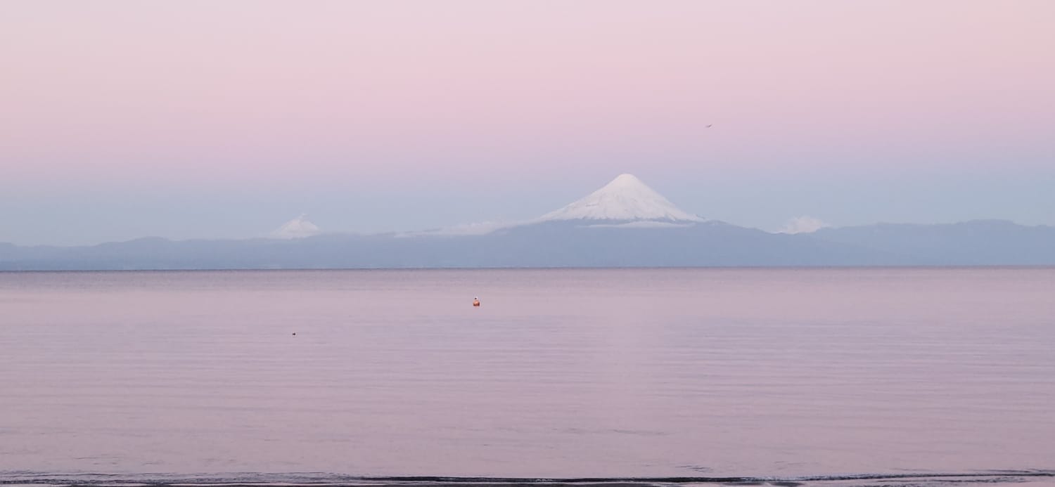 Lago y volcán bajo un cielo de tonos rosados
