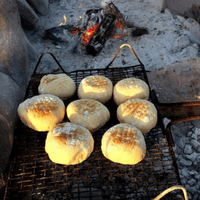 Traditional South African roosterkoek grilling over campfire coals during a Van Africa 4x4 overlanding adventure.