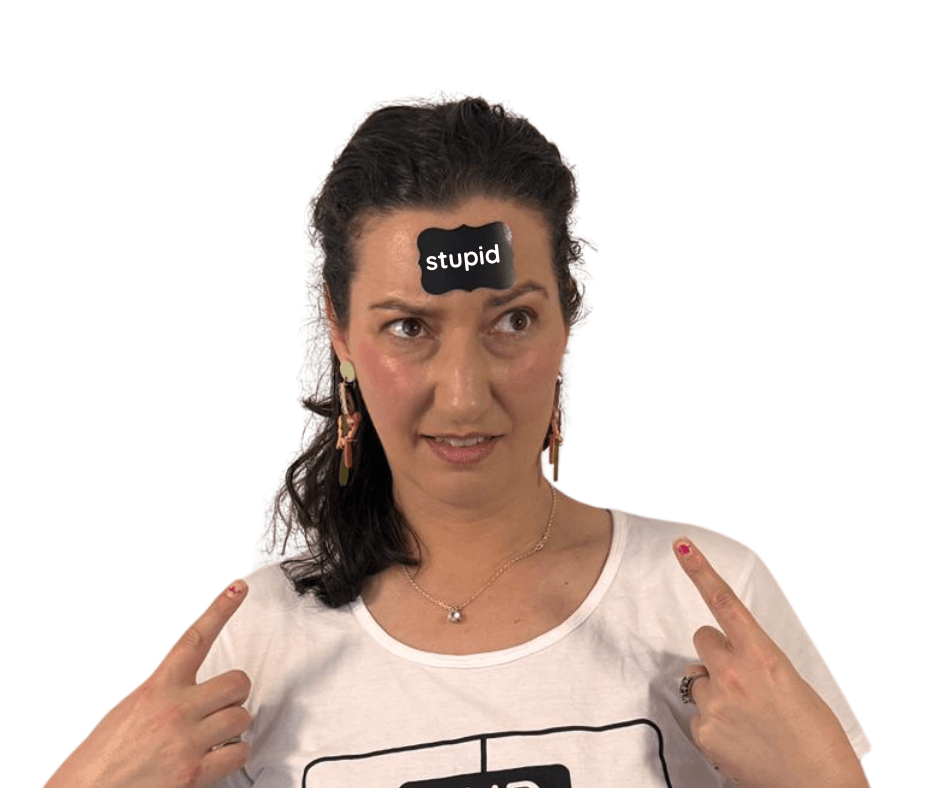 A pciture of Hanna Hosking, founder of the sensologist a neuroaffirming sex therapy practice www.thesensologist.com. She has the label stupid stuck to her head and is pointing at it with a quizzical look on her face. 