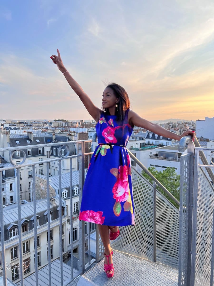 Hapsatou Sy sur un toit de Paris, bras levé