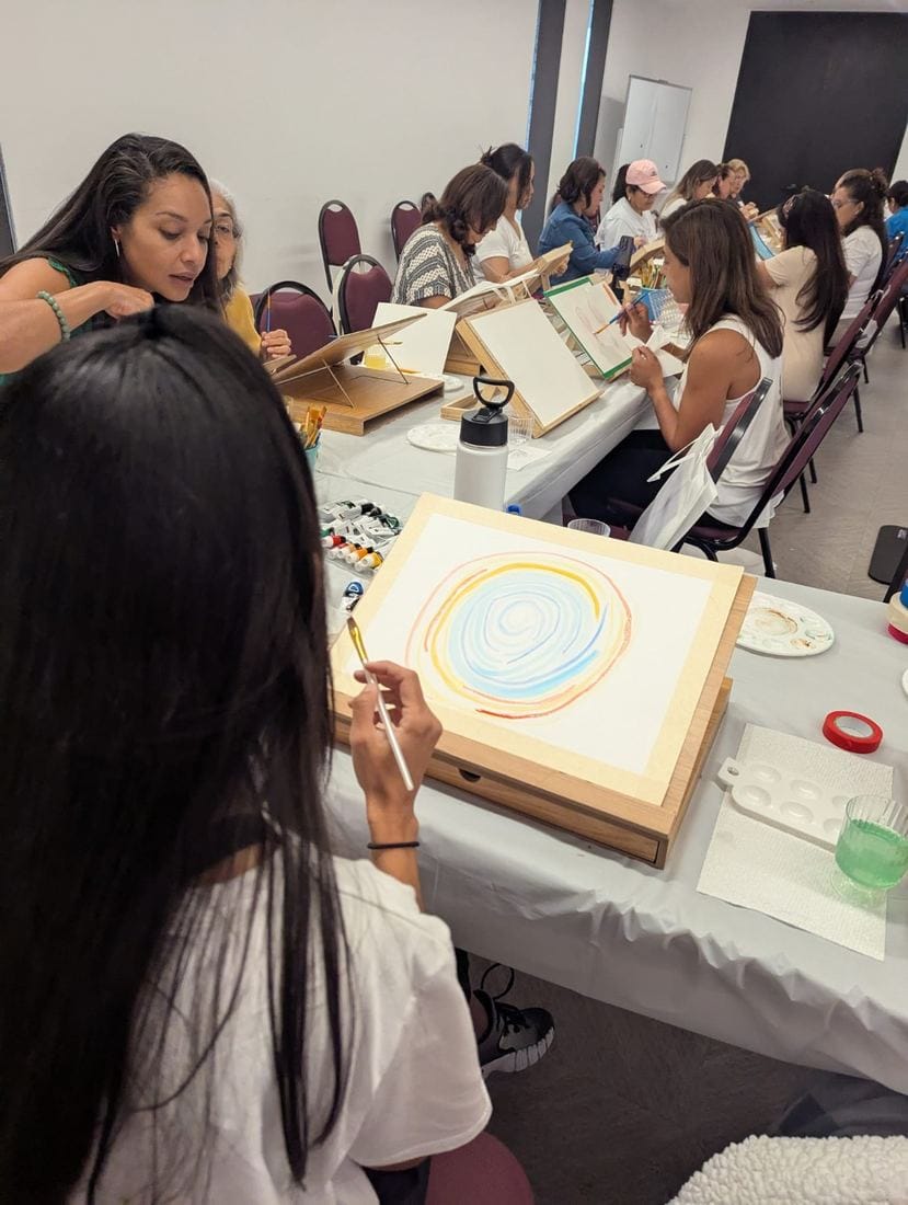 Ana K. Pinto acompañando a participantes pintando en un taller real de TransformArte