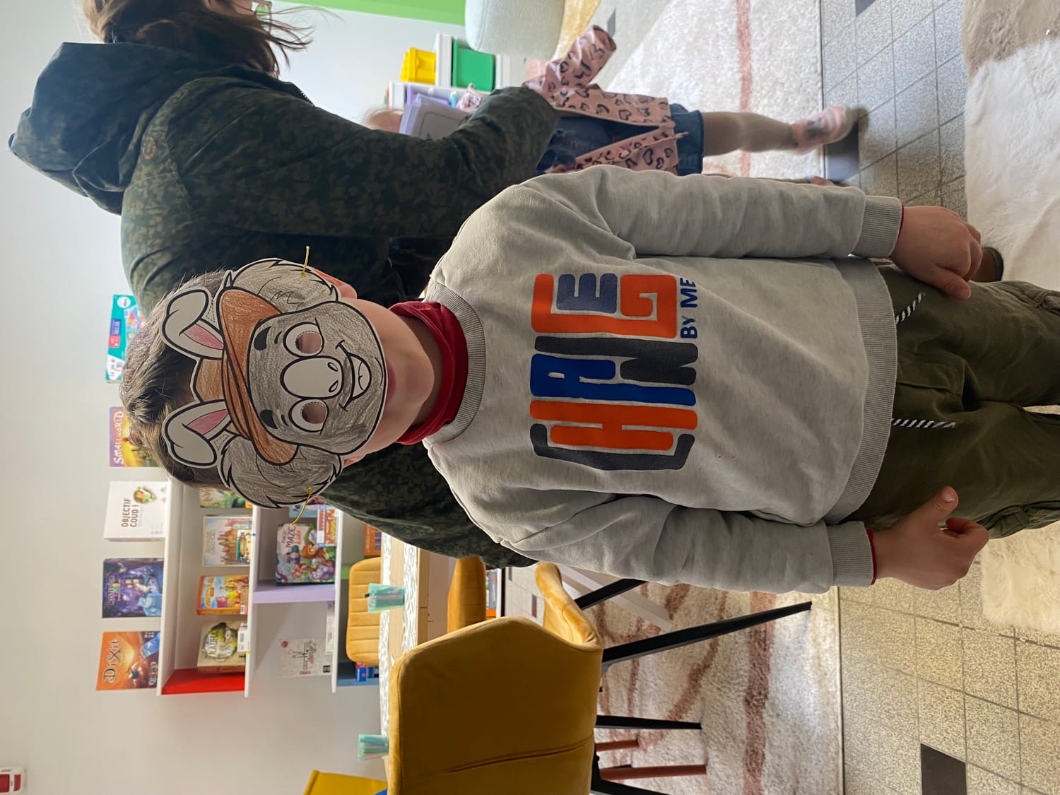 Enfants à la ludothèque de Coudekerque-Branche, coloriant avec application des masques de Pâques représentant le koala Mini Explorers avec des oreilles de lapin.