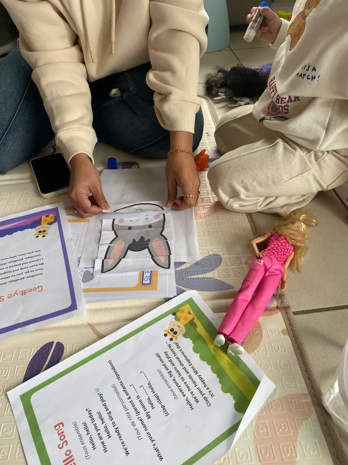 Enfants à la ludothèque de Coudekerque-Branche, coloriant avec application des masques de Pâques représentant le koala Mini Explorers avec des oreilles de lapin.