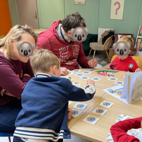 Enfants à la ludothèque de Coudekerque-Branche, coloriant avec application des masques de Pâques représentant le koala Mini Explorers avec des oreilles de lapin.