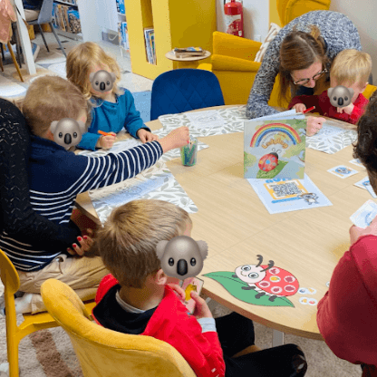 Enfants à la ludothèque de Coudekerque-Branche, coloriant avec application des masques de Pâques représentant le koala Mini Explorers avec des oreilles de lapin.