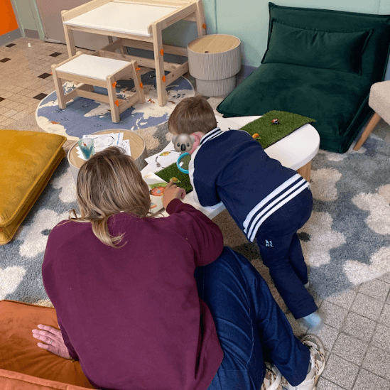 Enfants à la ludothèque de Coudekerque-Branche, coloriant avec application des masques de Pâques représentant le koala Mini Explorers avec des oreilles de lapin.