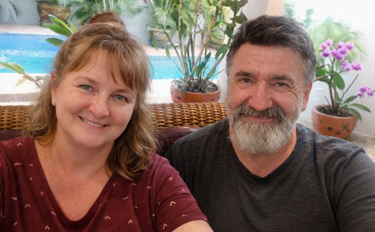 Tim and Sharyn smiling together beside a pool during a housesit