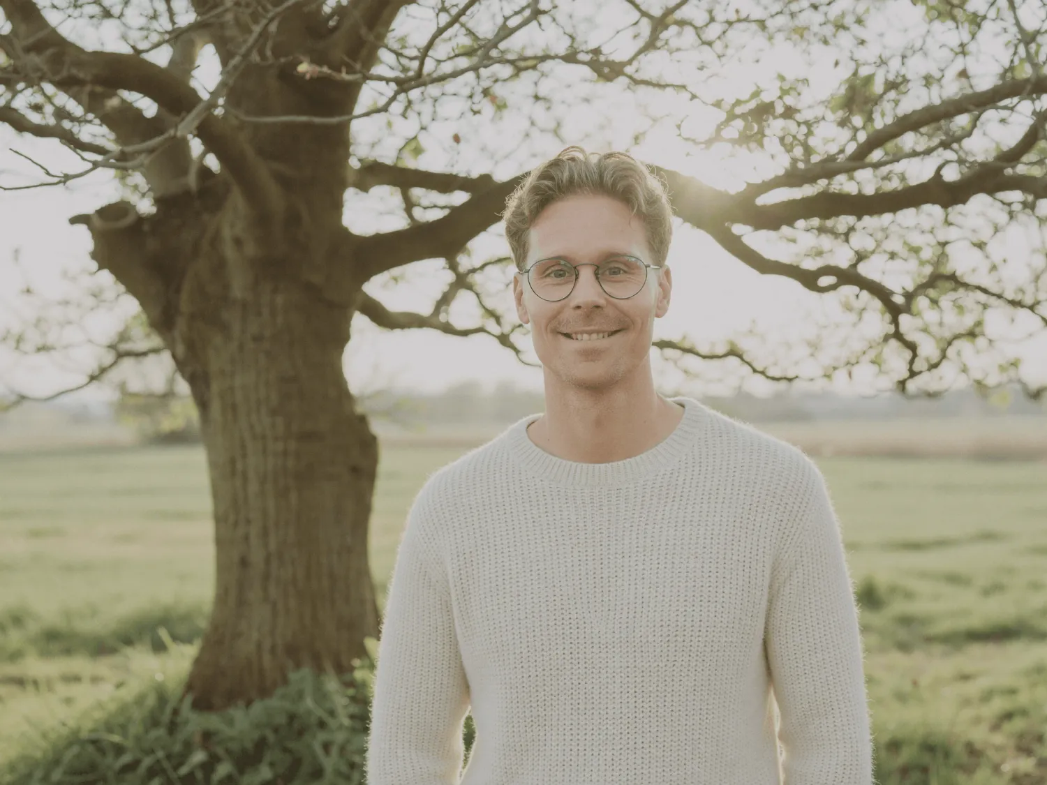 Daniel Müller vor einem Baum in einer sommerlichen Landschaft