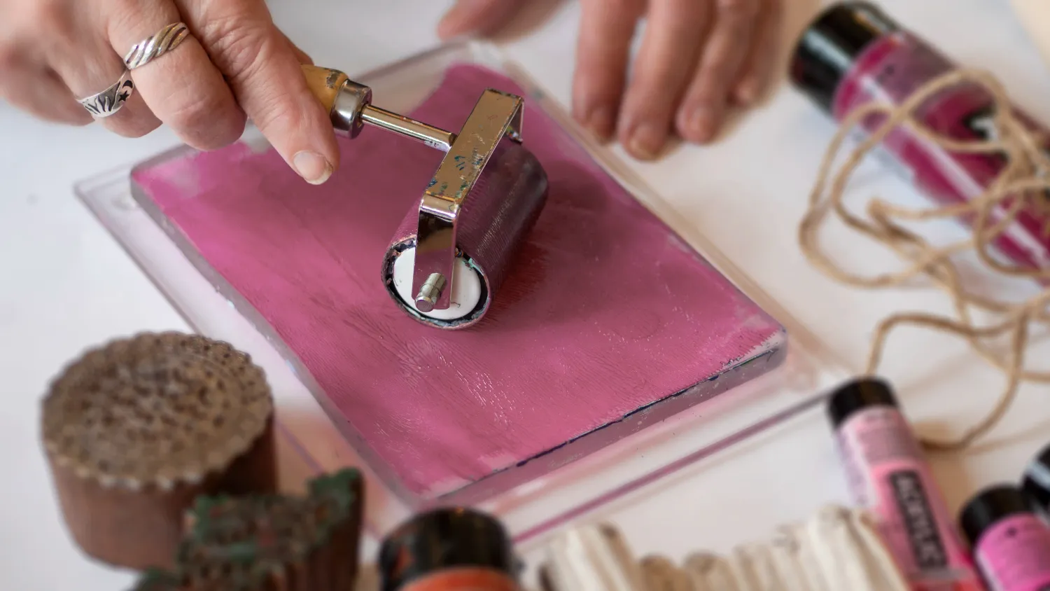 Roller met roze verf op de gelplate