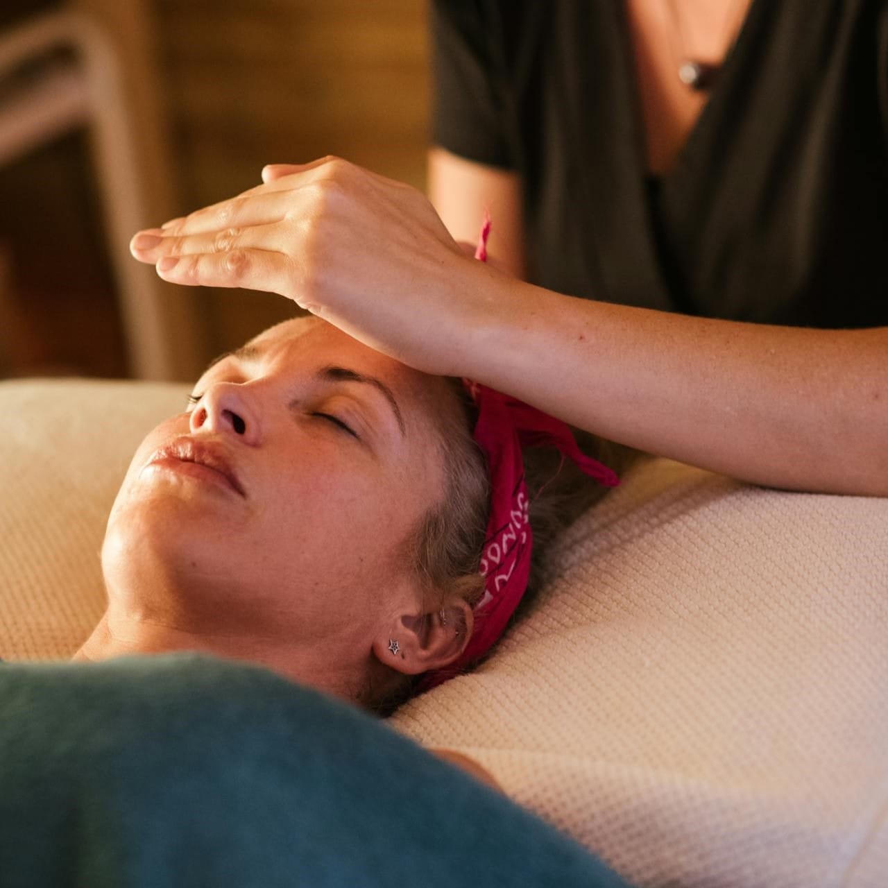 Νεαρή γυναίκα ξαπλωμένη δέχεται θεραπεία ρέικι