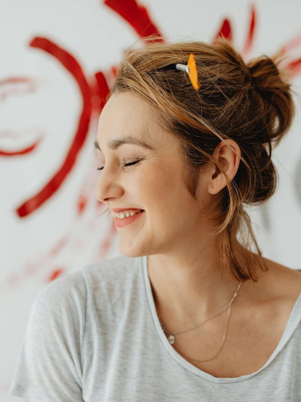 Μια γυναίκα στέκεται μπρόσταά από έναν τοίχο με ζωγραφίες χαμογελώντας