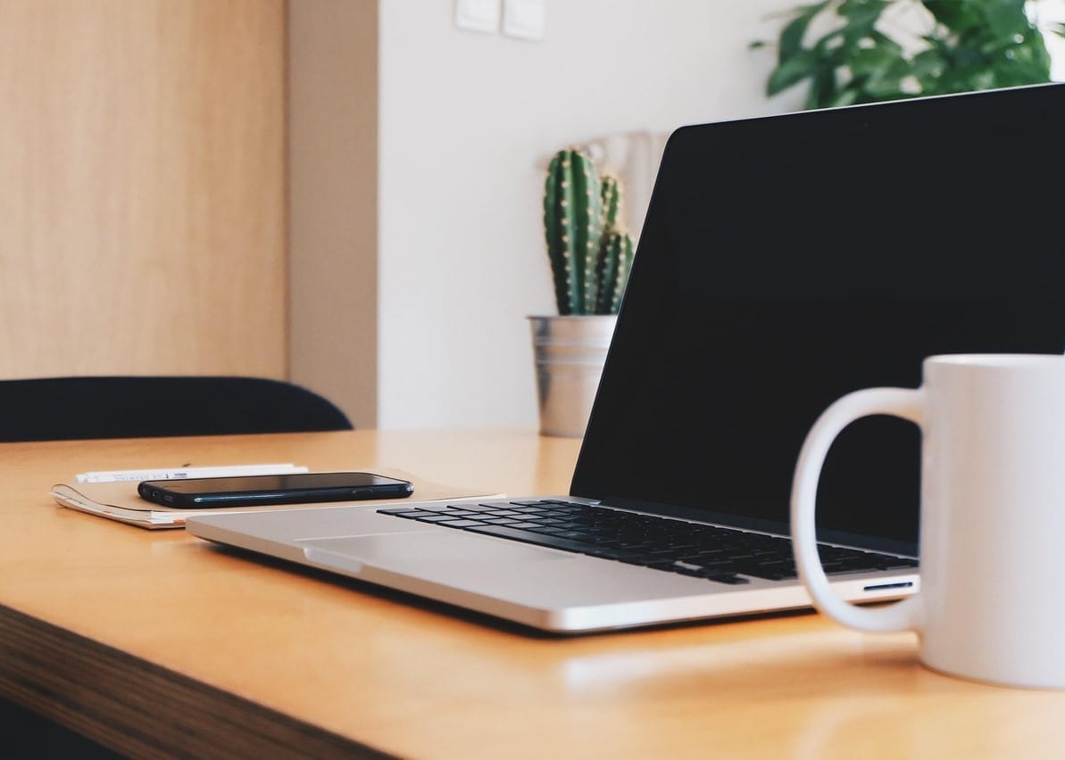 Ένα γραφείο που έχει επάνω υπολογιστή και κινητό τηλέφωνο