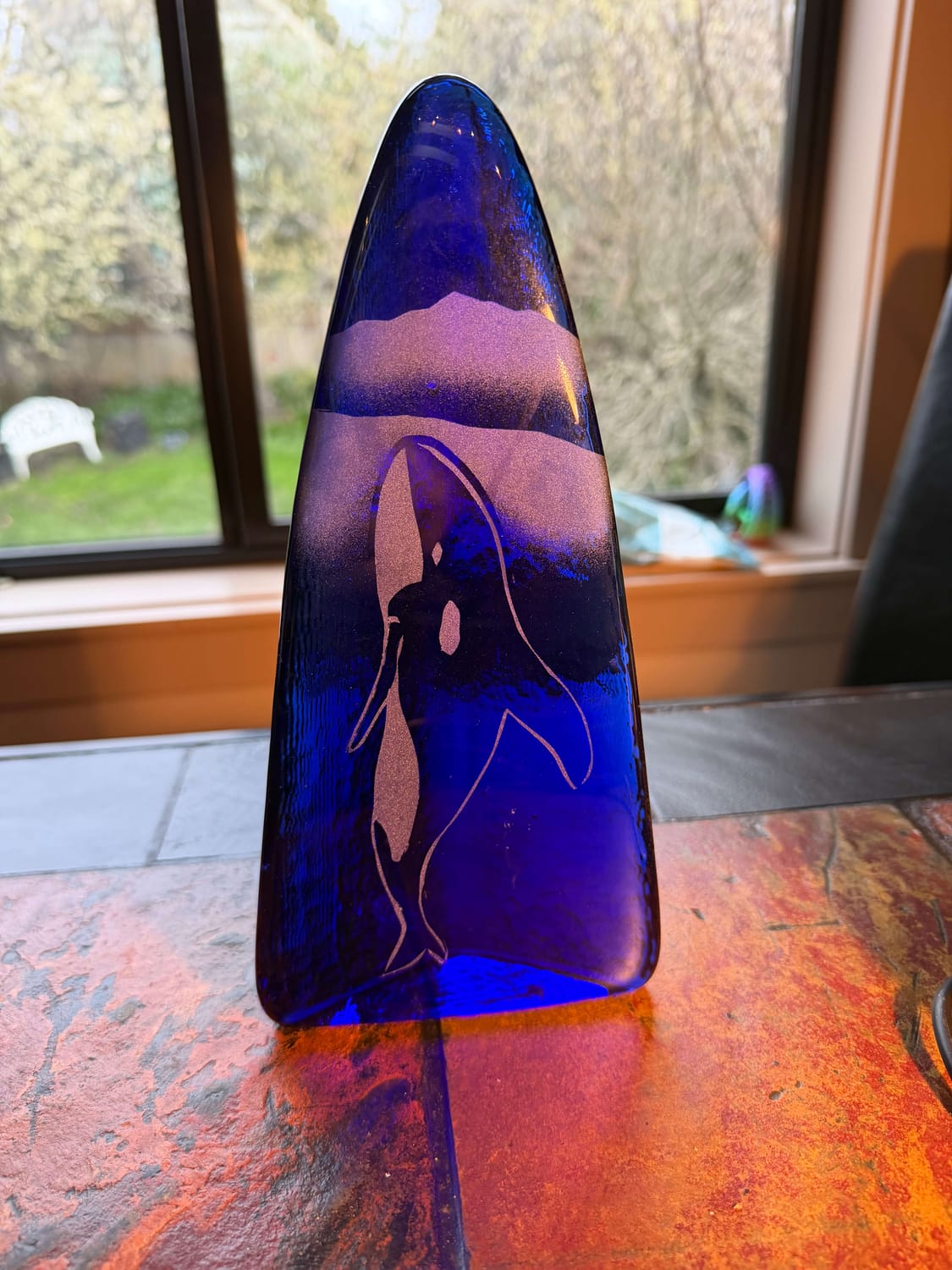 A handcrafted blue glass sculpture of an orca, created by Eric Pittman at his glass foundry, symbolizing his work with the Canadian Orca Rescue Society.