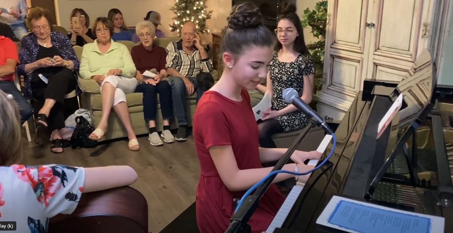 Teen playing & singing for family & friends on Sounds of Joy Music Studio private concert night.