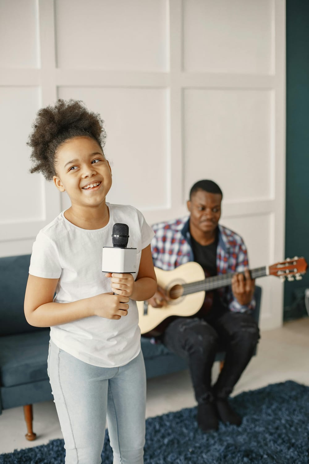 Young girl with mic practicing with dad on guitar.  Sounds of Joy Music Studio.