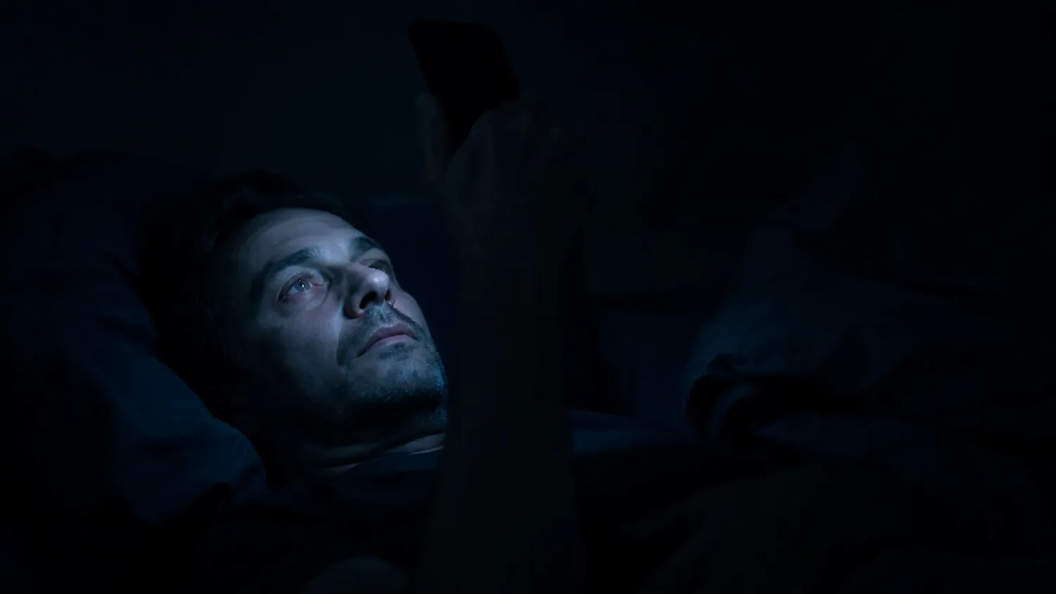 Man checking phone in bed at 3AM