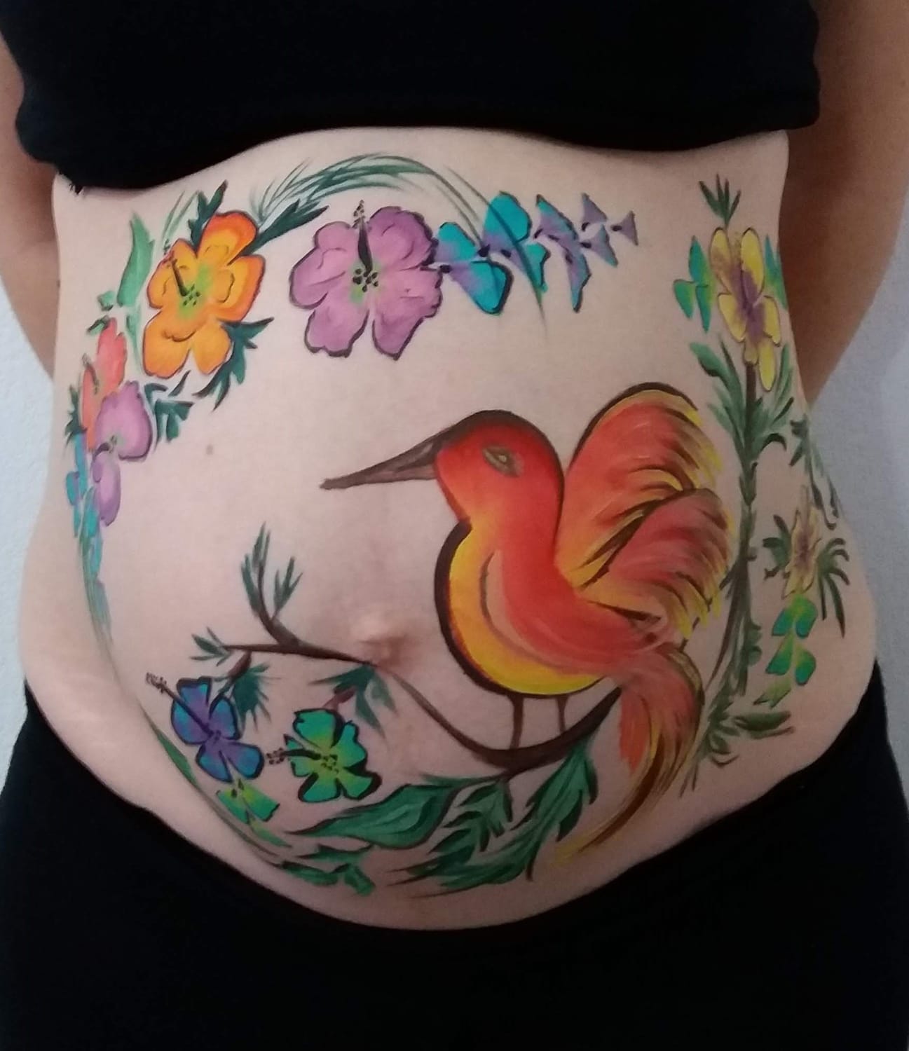 Motif artistique d’oiseau et fleurs en belly painting prénatal 