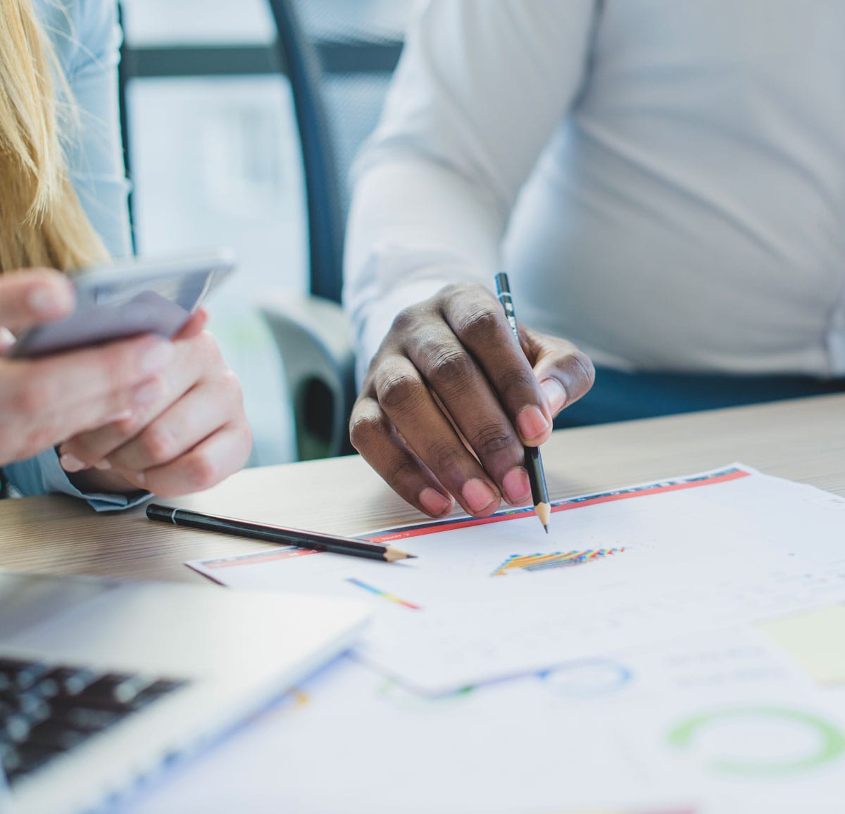 Office with man pointing with a pencil to graphic on the table 