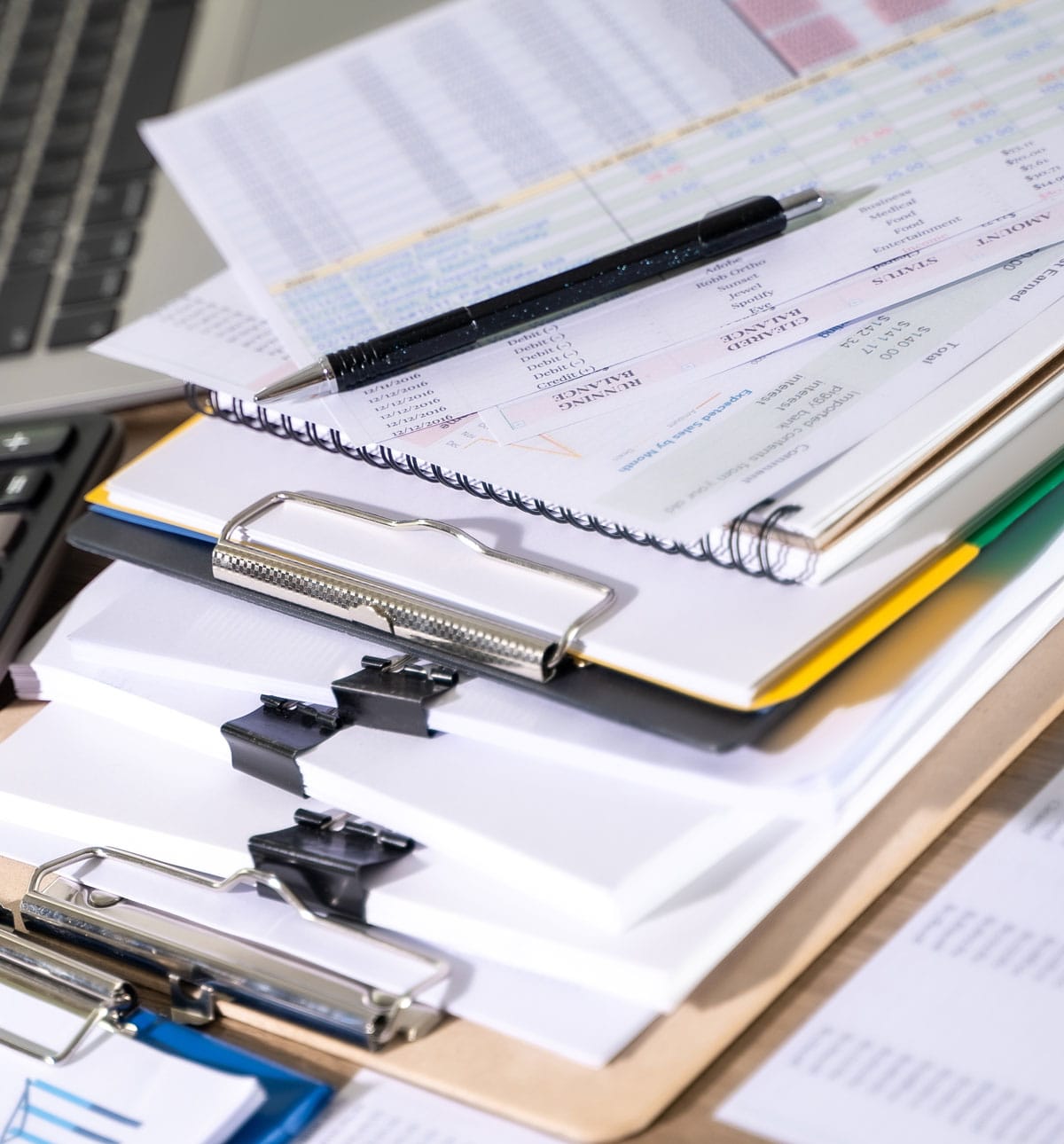 bookkeeping and payroll photo showing stacks of binder clipped paper and spreadsheets