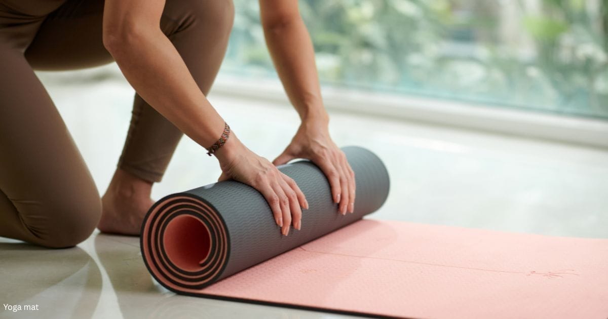 A woman rolling up her yoga mat after a workout