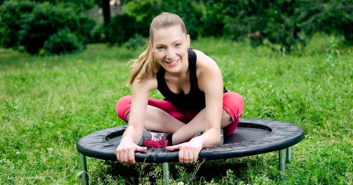 A young woman sitting and stretching on a mini rebounder
