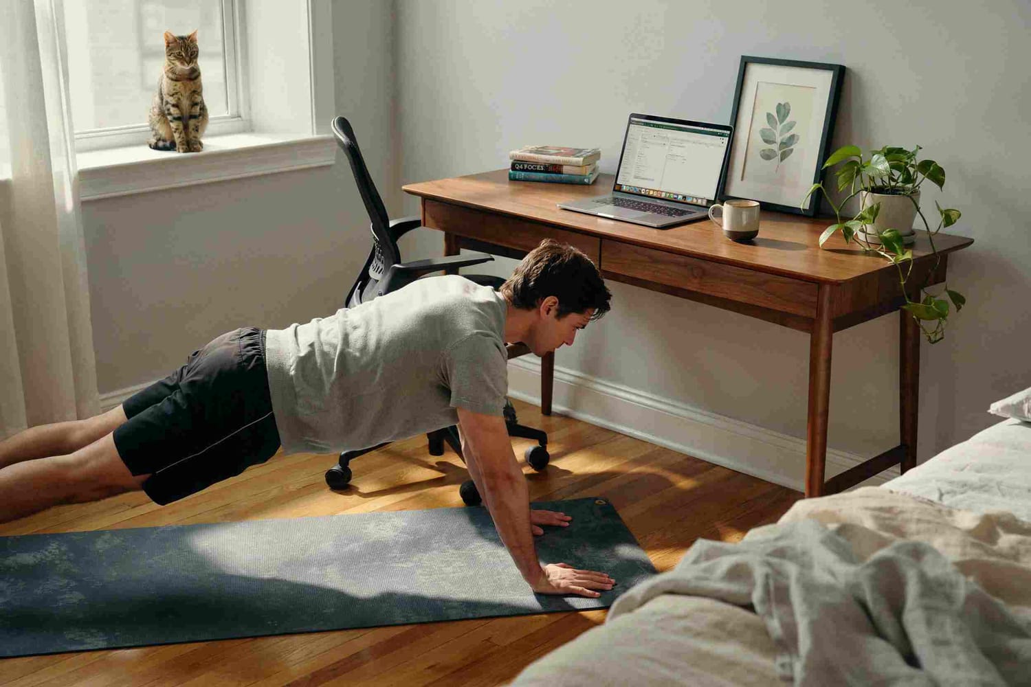 A person doing push-ups next to their home office desk