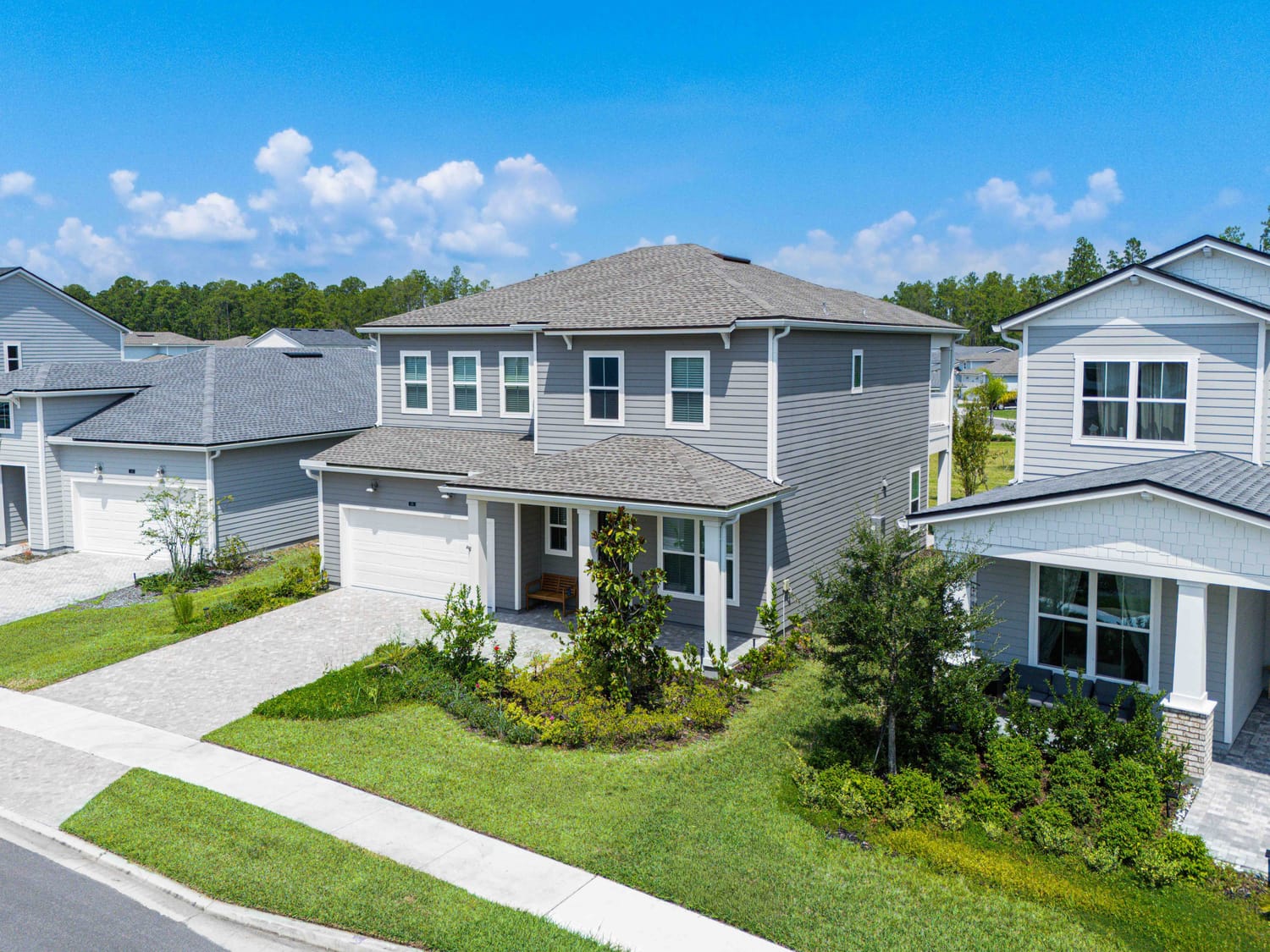 Elevated front-angled drone photo of a suburban luxury home, emphasizing curb appeal and architectural design.