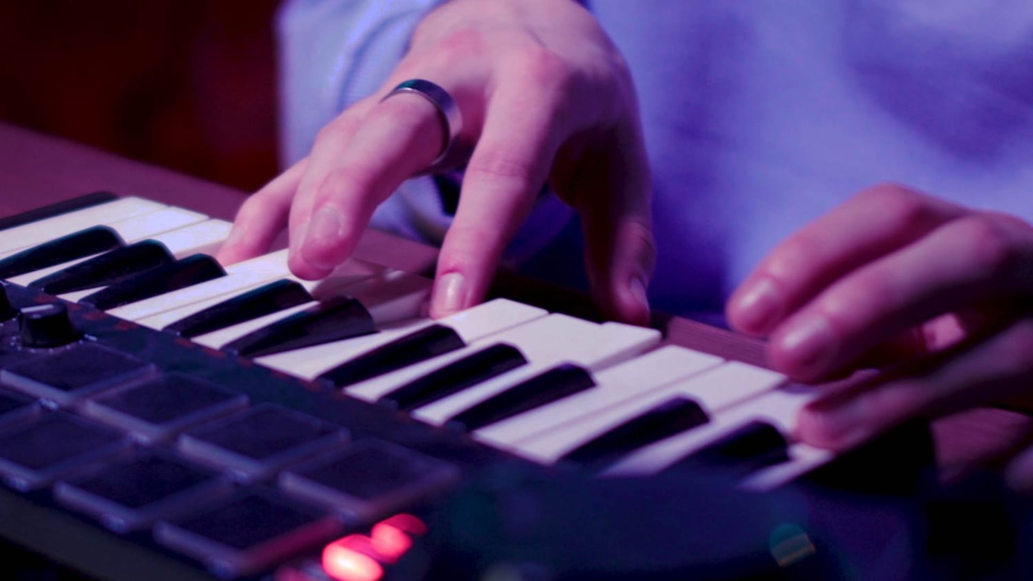 A close‑up of hands playing a small MIDI keyboard with performance pads, representing the transition from understanding MIDI basics to creating expressive musical ideas.