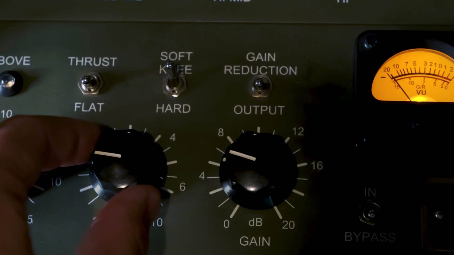 A close‑up of a hardware compressor with a hand adjusting the controls, illustrating how compression shapes dynamics and controls peaks in a mix.