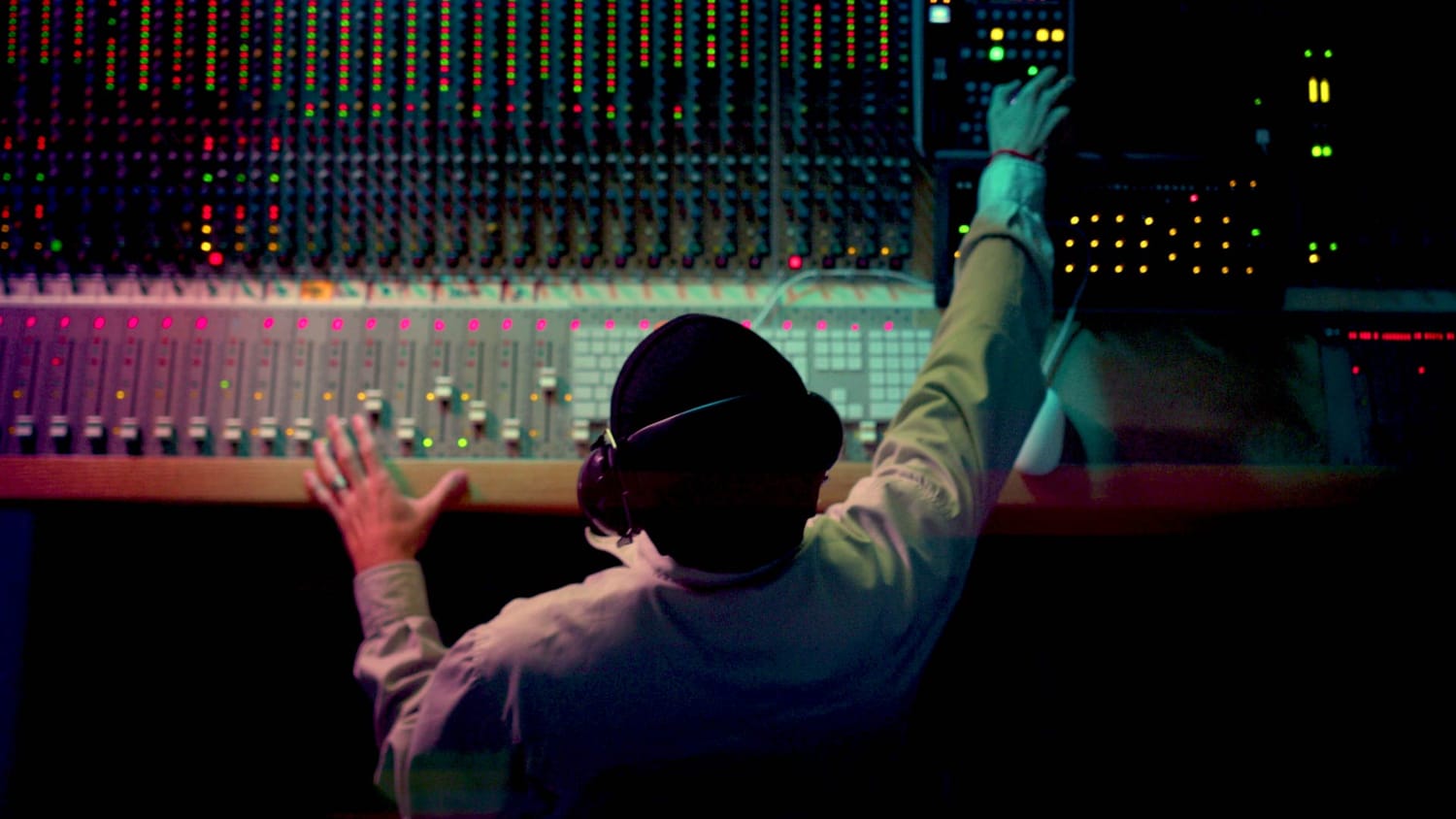 Analog mixer console being operated by a mixing engineer as he works on a song.  