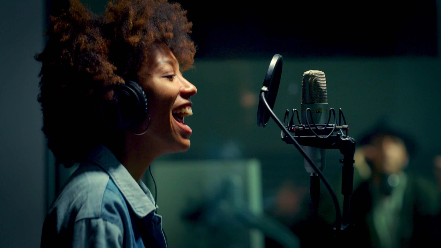 A vocalist recording into a studio microphone while wearing headphones, illustrating how Sparkflow helps musicians capture ideas clearly and confidently.
