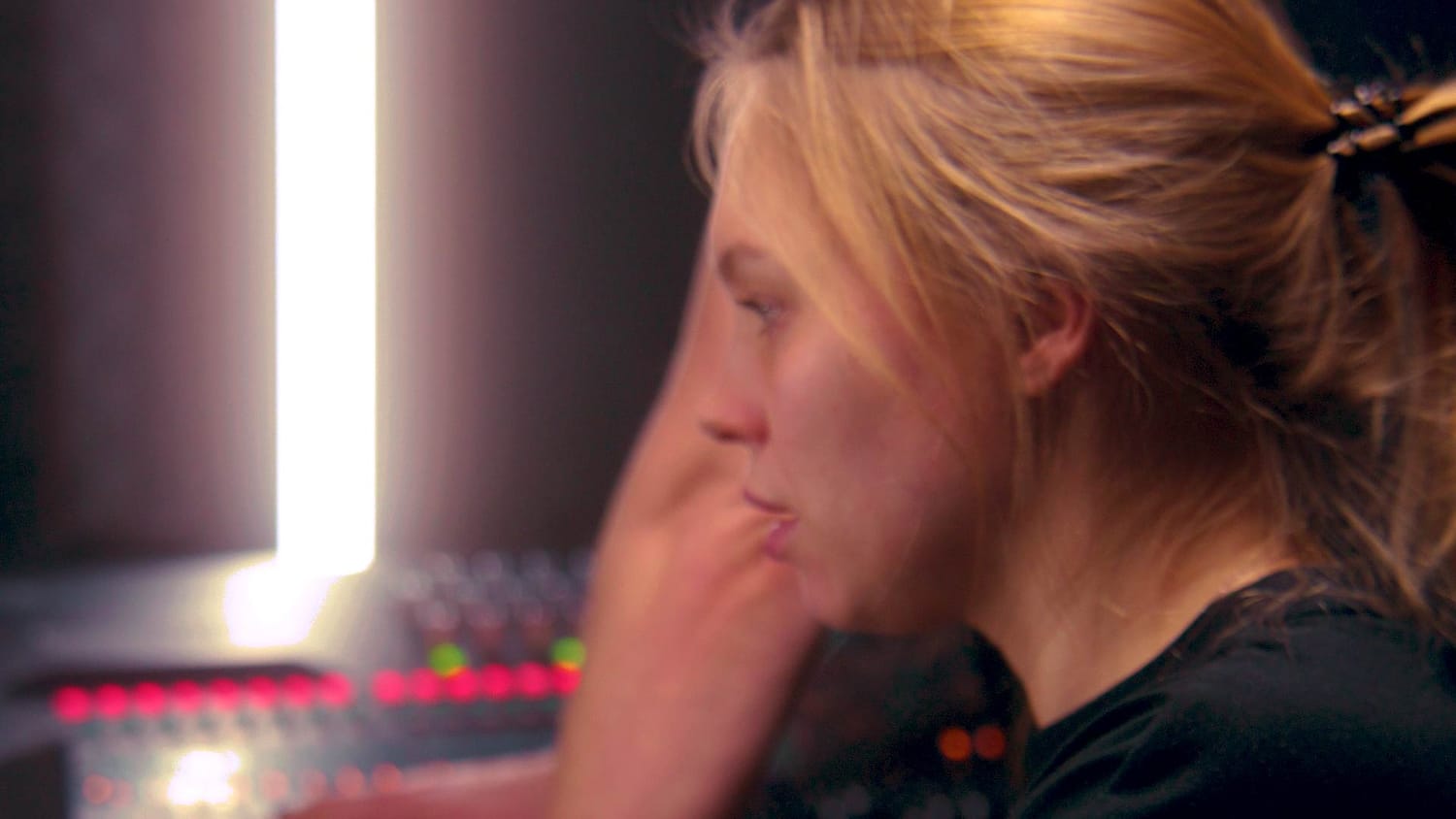 A beginner producer sitting at a soundboard with glowing controls, symbolizing the foundational concepts and practical clarity offered inside the Pre‑Ignition Brief.