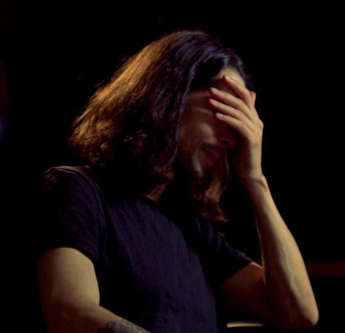A person sitting in dim light with their head in their hand, expressing the frustration and overwhelm beginners often feel when trying to make music for the first time.