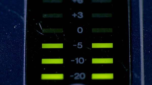 Analog mixer console with illuminated volume meters indicating levels during mixing and mastering.