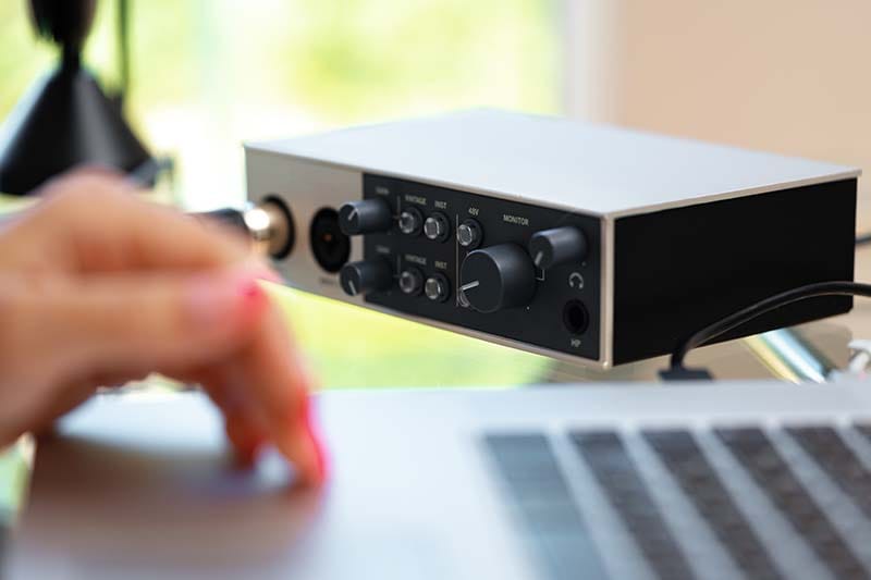 An audio interface connected to a laptop sitting on a desk.